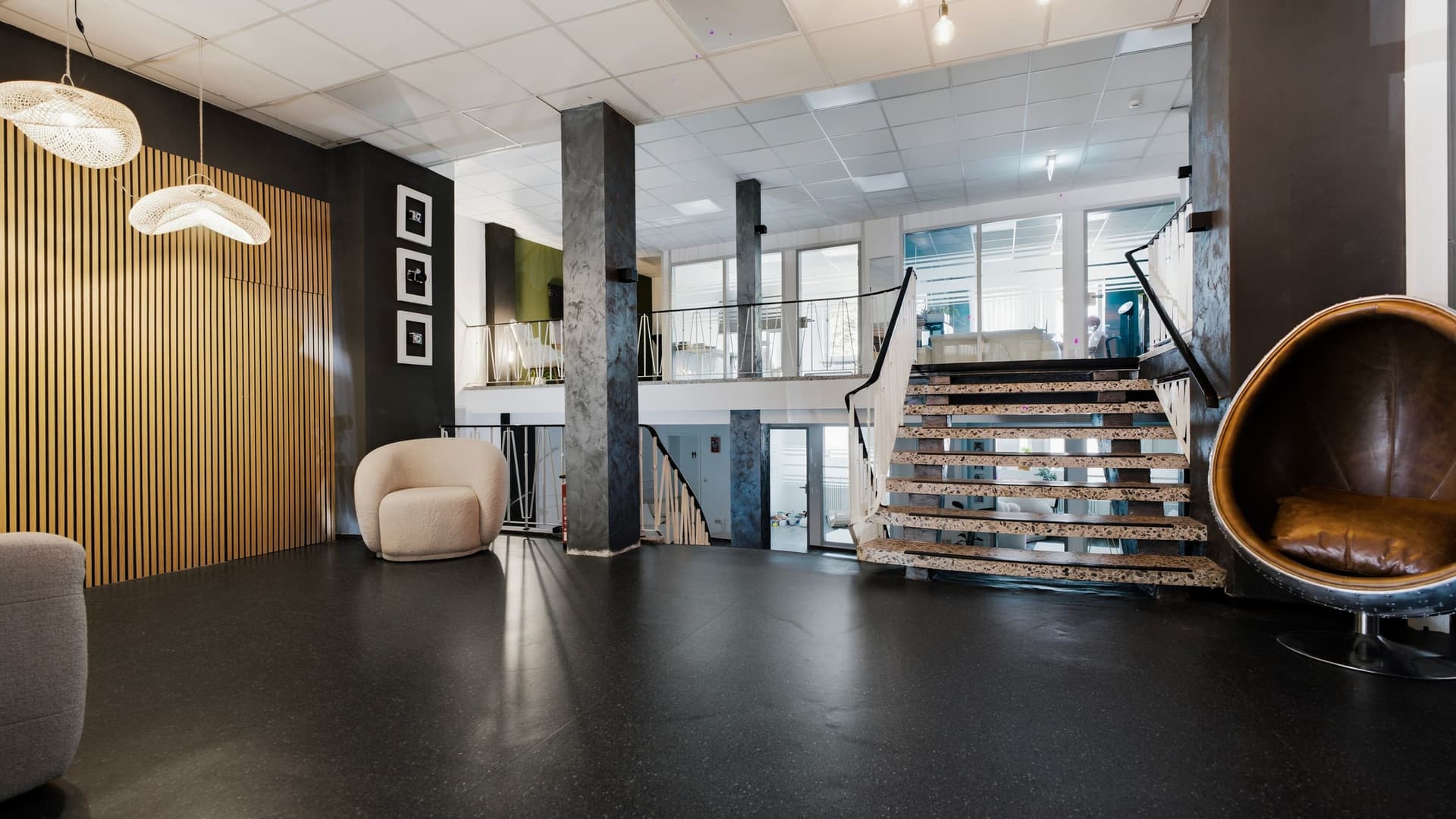 Studiohalle mit offener Treppe, Holz-Latten-Wand und Egg-Chair
